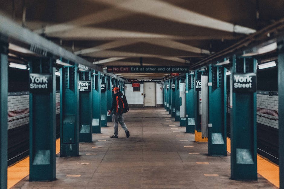 A silhouette of a man standing on the platform of Yichangdong Railway Station, which is covered by a large, modern metal roof structure with visible beams and supporting columns. The platform surface